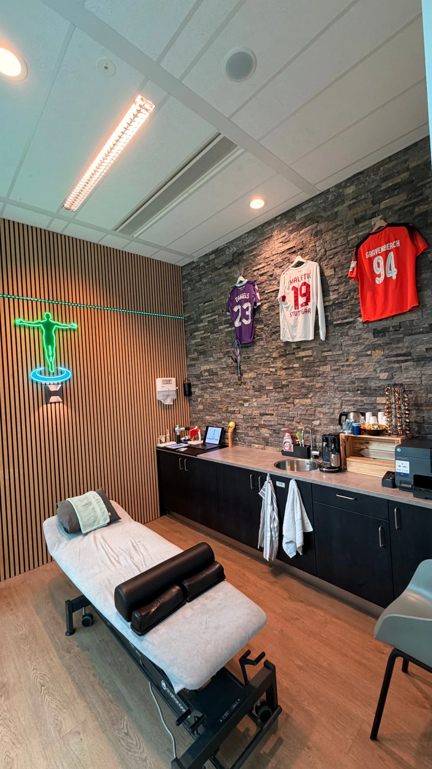 Gesigneerde shirts van profvoetballers aan de stenen wand van de behandelkamer